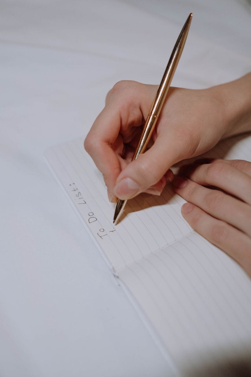 A hand writing 'To Do List' at the top of a lined page
