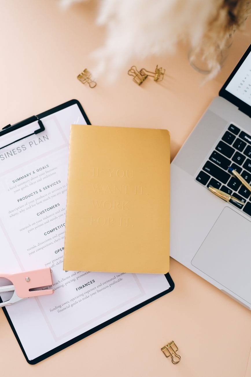 A notebook reading 'if you want it, work for it' resting on a written plan — the doing mindset of an action board