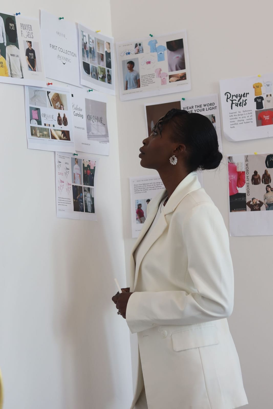 A woman studying a wall of pinned-up mood board and brand references