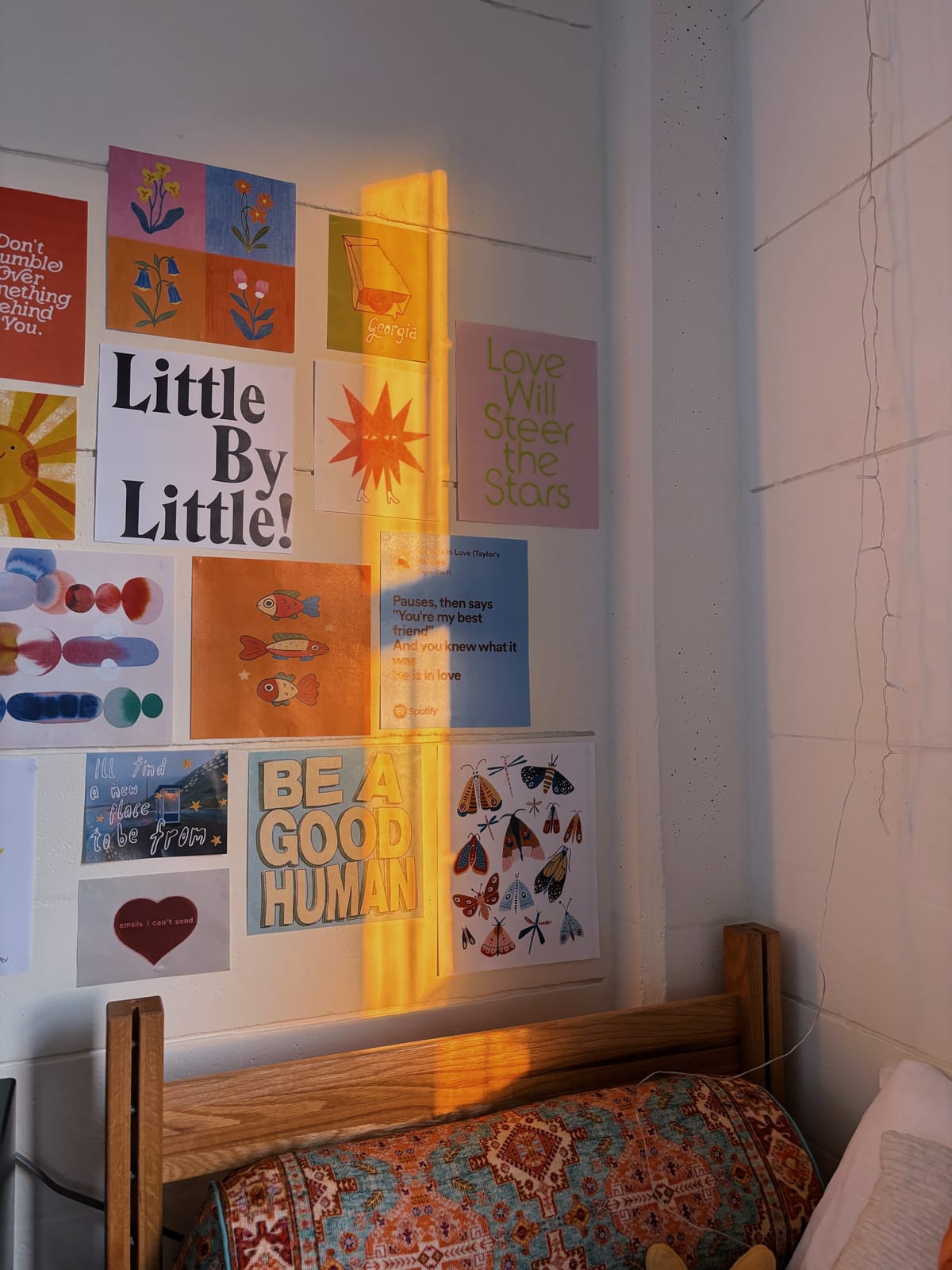 A bedroom poster wall of prints, quotes, and illustrations