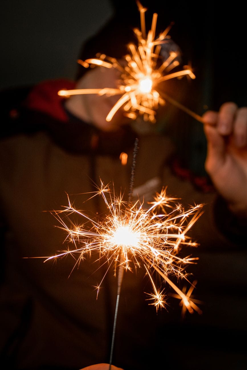 Two lit sparklers held up in the dark to celebrate the new year
