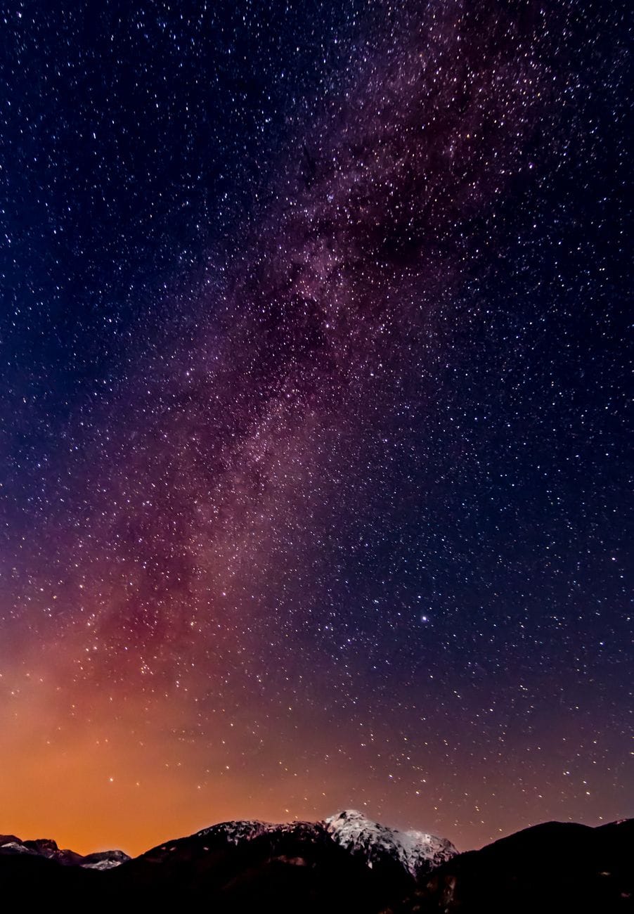 A star-filled night sky and Milky Way over dark mountains