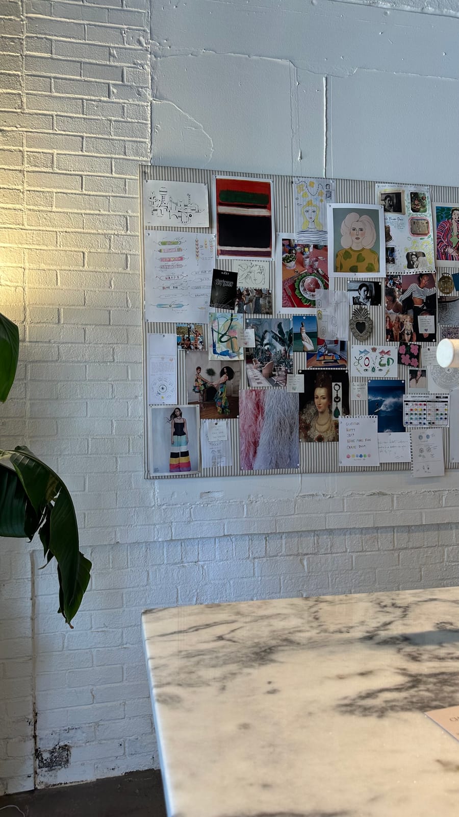 An analog vision board pinned to a striped board on a white brick wall