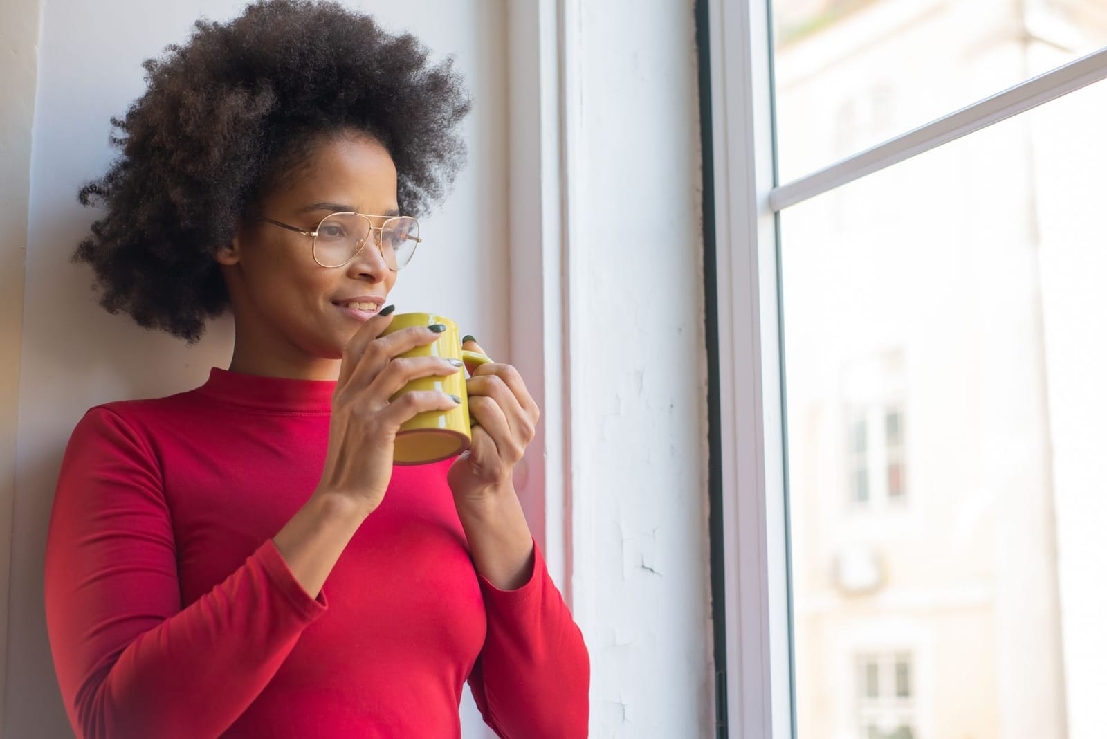 A woman with a warm drink envisioning her goals — the mindset behind a vision board